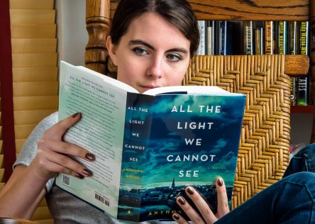 A woman reading the book All the Light We Cannot See