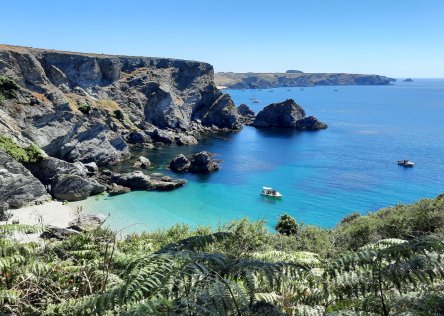 A beautiful beach in Brittany on Belle Ile island. The sea is turquoise and the sand is white. There are cliffs above the beach.