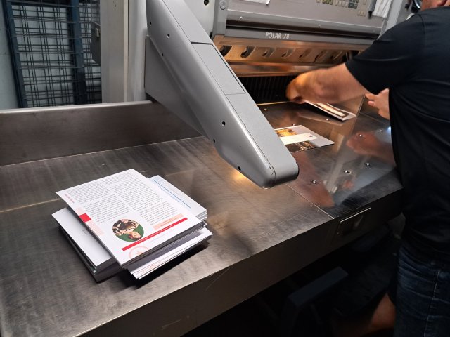 Laurent using a machine to cut the pages of the guidebook