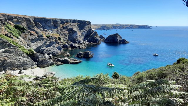 Panoramic clifftop view of the beach on Belle Ile island. The sandy beach is white, the sea is several different colors of turquoise and blue.