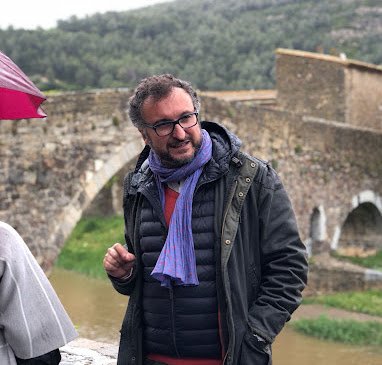 Tour Guide & French Genealogist, Carlos Lluch with a stone bridge over a river in the background