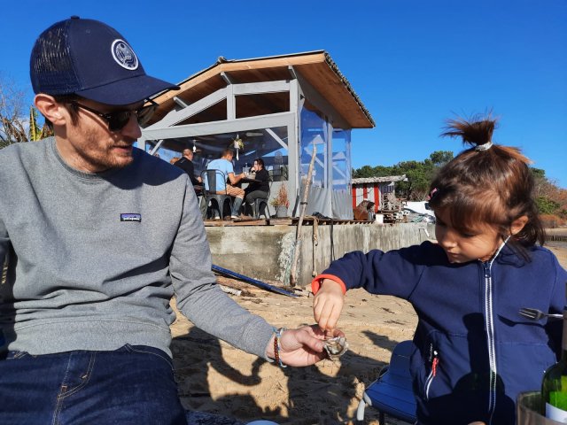 Trip planner Emilie's daughter Pauline trying fresh oysters in Arcachon Bay in Bordeaux A man offering a girl a fresh oyster to try in Bordeaux