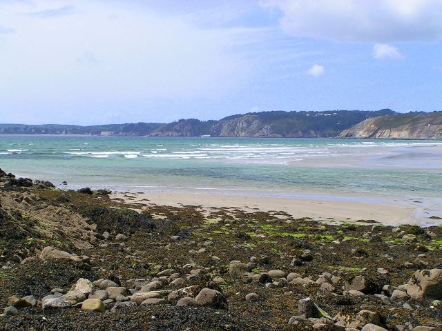Plage de l'Aber in Brittany. The beach with the sea and cliffs in the background, stones in the foreground.