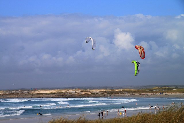 The beach at Plage de la Torche in Brittany. The waves are big and there are people surfing and kite-surfing