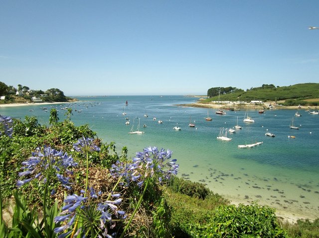 Saint Pabu beach, with a green-turquoise sea and sailing boats bobbing in the distance.