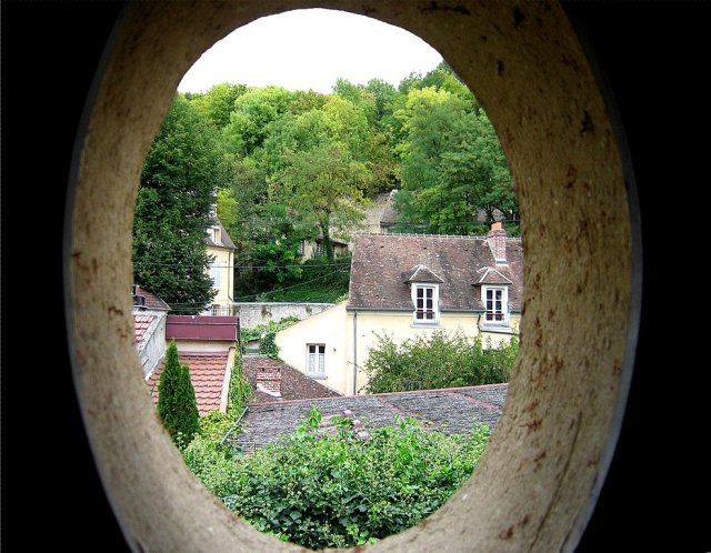 View through an oval shaped window in a staircase leading up to van Gogh's attic room in Auvers-sur-Oise