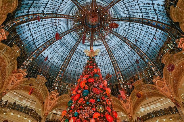Christmas tree with decorations and lights below a glass domed roof at Galeries Lafayette in Paris