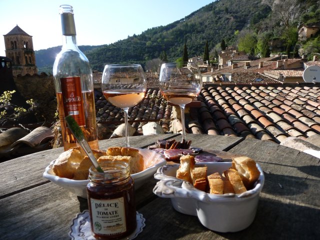 A bottle and glasses of Rose wine and a picnic lunch with pretty green Provence scenery in the background