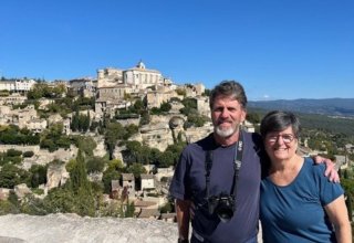 Travelers Judy and Michael with the village of Gordes, Provence, in the background