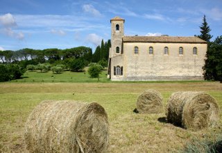 Lourmarin, Provence A green field with haystacks in it and an abbey in the background in Lourmarin, Provence