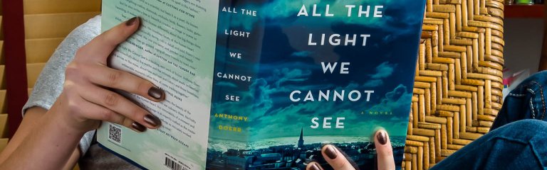 A woman reading the book All the Light We Cannot See