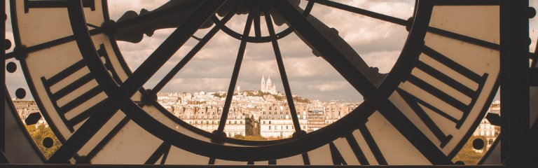 The clock at the Orsay Museum in Paris, with a view of the city through the glass