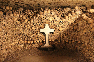 Bones and skulls that line the walls of the Paris Catacombs, with a cross in the middle